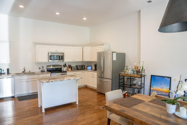 kitchen featuring dark hardwood / wood-style flooring, light stone counters, stainless steel appliances, sink, and white cabinetry