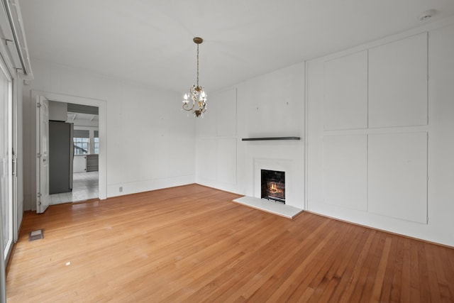 unfurnished living room featuring a chandelier and hardwood / wood-style flooring