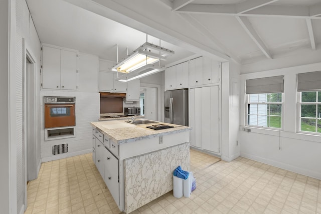 kitchen featuring vaulted ceiling with beams, a center island, white cabinetry, and appliances with stainless steel finishes