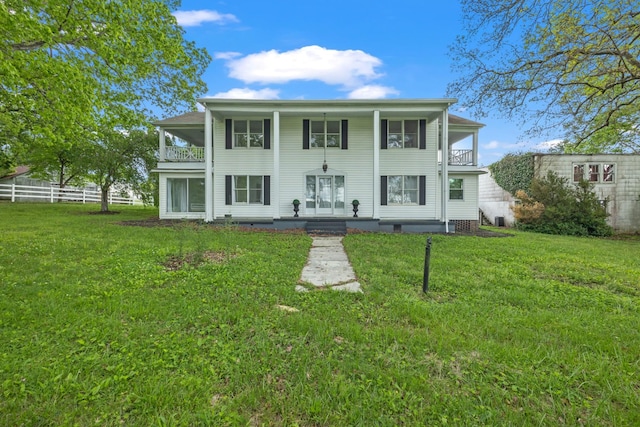 back of property with a lawn and a balcony