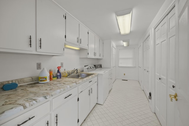 kitchen featuring white cabinetry, washer and clothes dryer, and sink