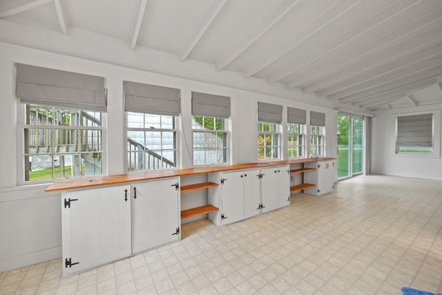 unfurnished sunroom featuring beamed ceiling