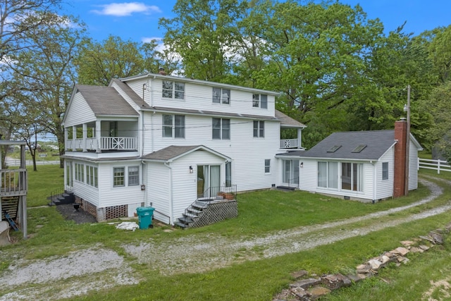 rear view of property with a balcony and a yard