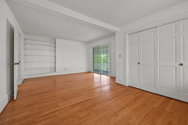 unfurnished bedroom with a closet, a textured ceiling, and light wood-type flooring