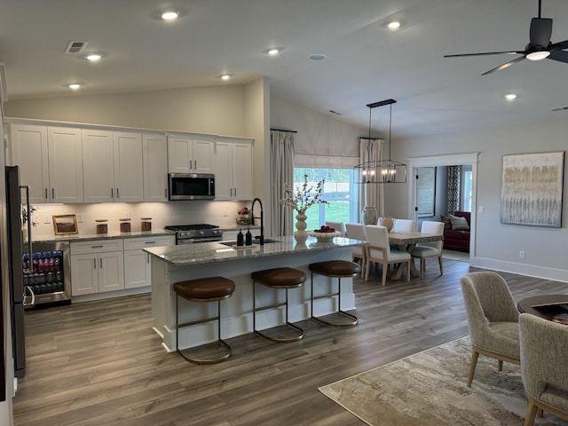 kitchen with a center island with sink, dark hardwood / wood-style floors, white cabinets, and appliances with stainless steel finishes