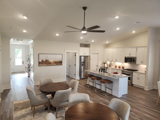 dining room featuring ceiling fan, dark hardwood / wood-style flooring, lofted ceiling, and sink