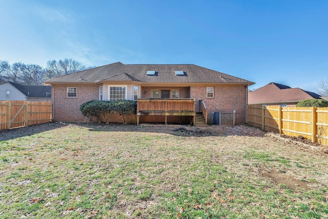 rear view of house featuring cooling unit, a lawn, and a wooden deck