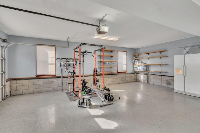 garage featuring white refrigerator with ice dispenser and a garage door opener