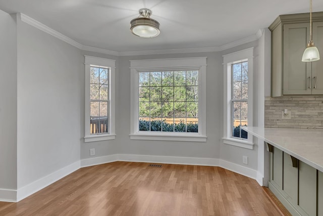 unfurnished dining area with light wood-type flooring, plenty of natural light, and ornamental molding