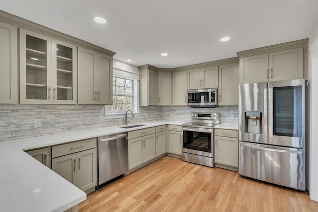 kitchen with gray cabinets, stainless steel appliances, light hardwood / wood-style flooring, and sink