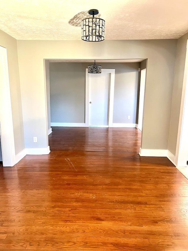 unfurnished dining area featuring a notable chandelier, wood-type flooring, and a textured ceiling