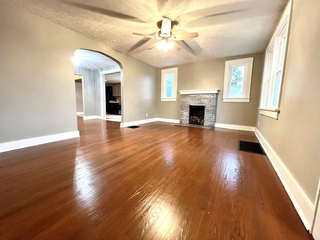 unfurnished living room with hardwood / wood-style floors, a fireplace, ceiling fan, and a textured ceiling