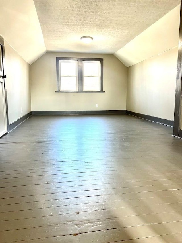 bonus room with a textured ceiling, hardwood / wood-style flooring, and lofted ceiling