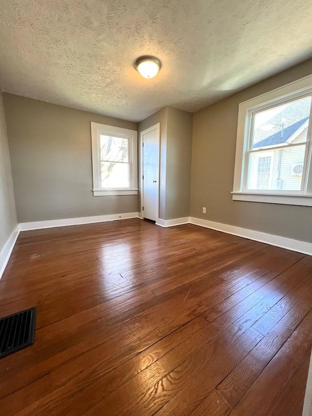 spare room featuring plenty of natural light, dark hardwood / wood-style flooring, and a textured ceiling