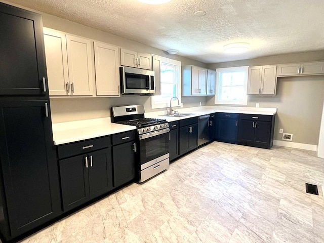 kitchen featuring a textured ceiling, sink, white cabinetry, and stainless steel appliances