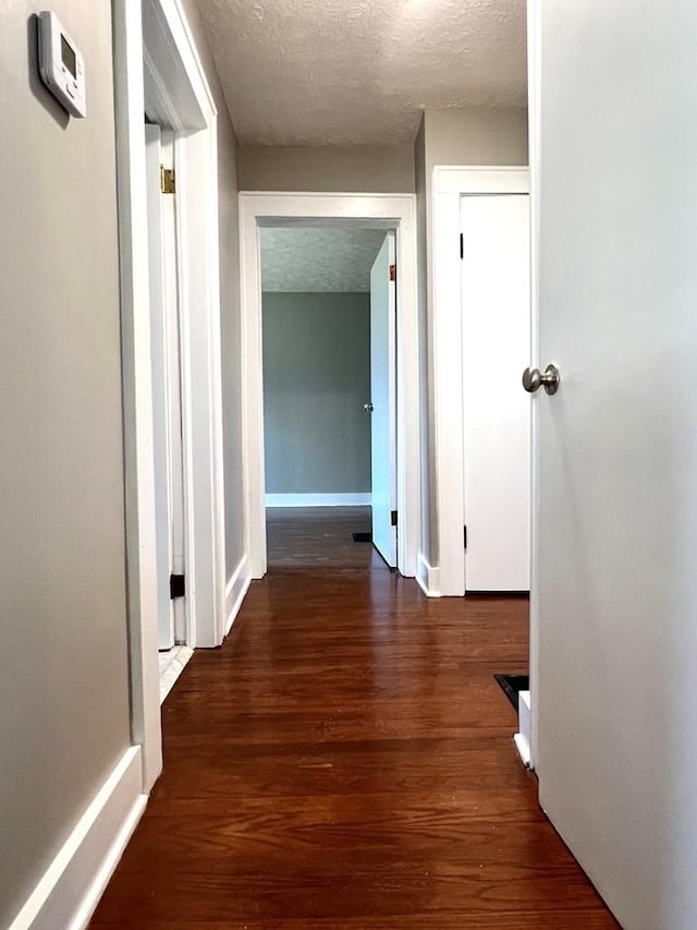 hall featuring dark hardwood / wood-style flooring and a textured ceiling