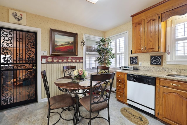 kitchen with sink, dishwasher, and light stone counters