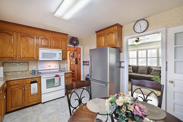 kitchen with white appliances, light stone countertops, and ceiling fan