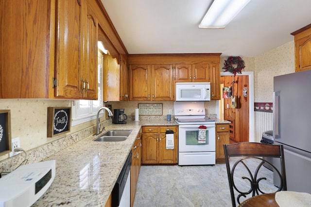 kitchen with stainless steel appliances, light stone countertops, and sink