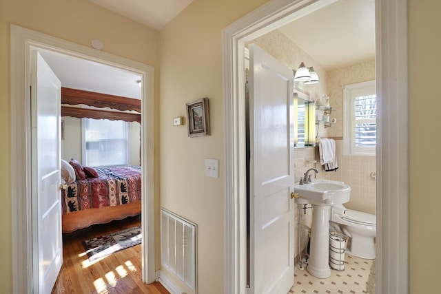 bathroom featuring tile walls, hardwood / wood-style flooring, and toilet