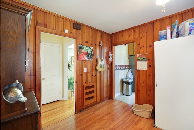 hall with wood walls, ornamental molding, and light hardwood / wood-style floors