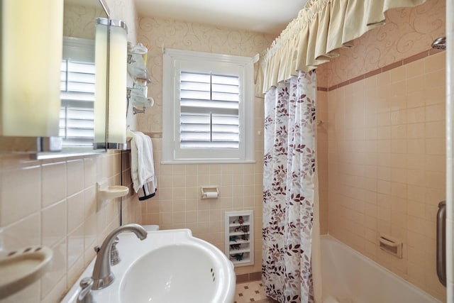 bathroom with shower / bathtub combination with curtain, tile walls, and sink