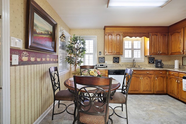 kitchen featuring sink, white dishwasher, and light stone countertops