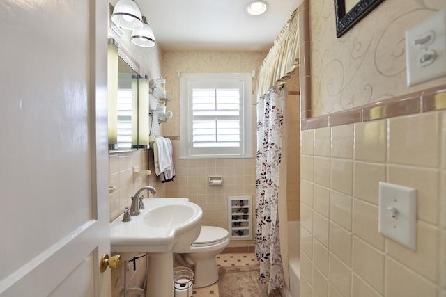 full bathroom with sink, tile walls, toilet, tile patterned floors, and shower / bath combo with shower curtain