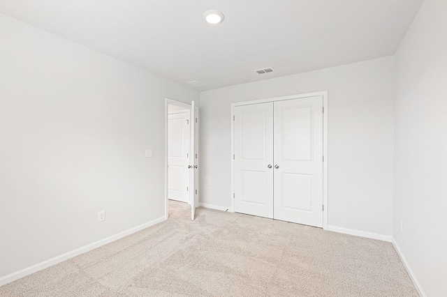 unfurnished bedroom with light carpet and a closet