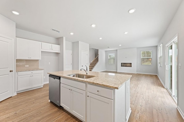 kitchen with white cabinets, dishwasher, a fireplace, and sink