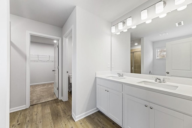 bathroom featuring toilet, vanity, a shower with door, and hardwood / wood-style flooring