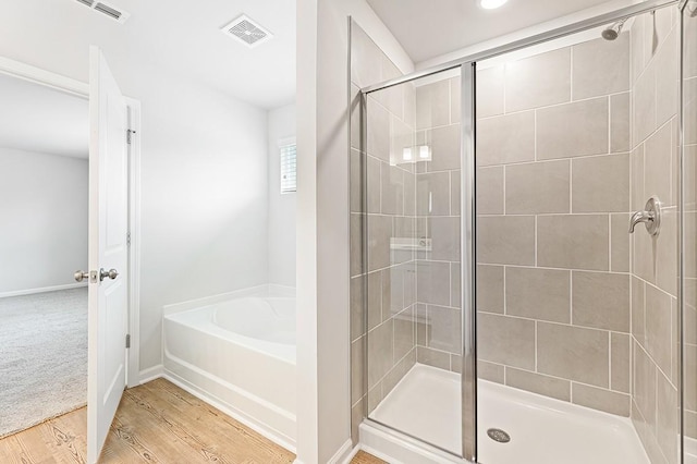 bathroom with separate shower and tub and wood-type flooring