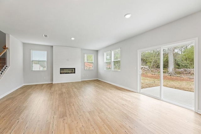 unfurnished living room with a wealth of natural light, a fireplace, and light hardwood / wood-style flooring