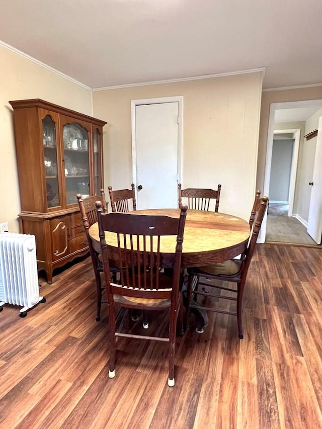 dining room featuring dark hardwood / wood-style floors, crown molding, and radiator