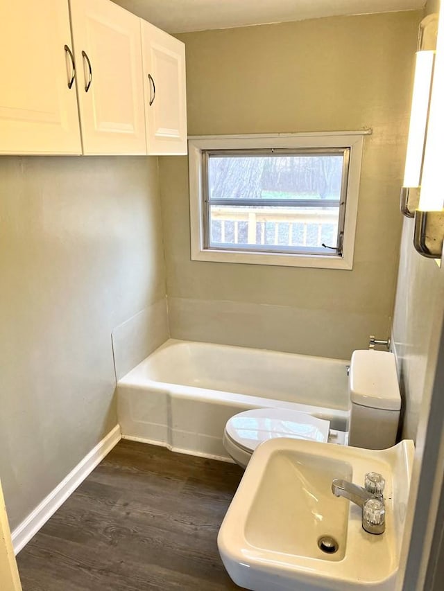 bathroom featuring wood-type flooring, toilet, a bathing tub, and sink