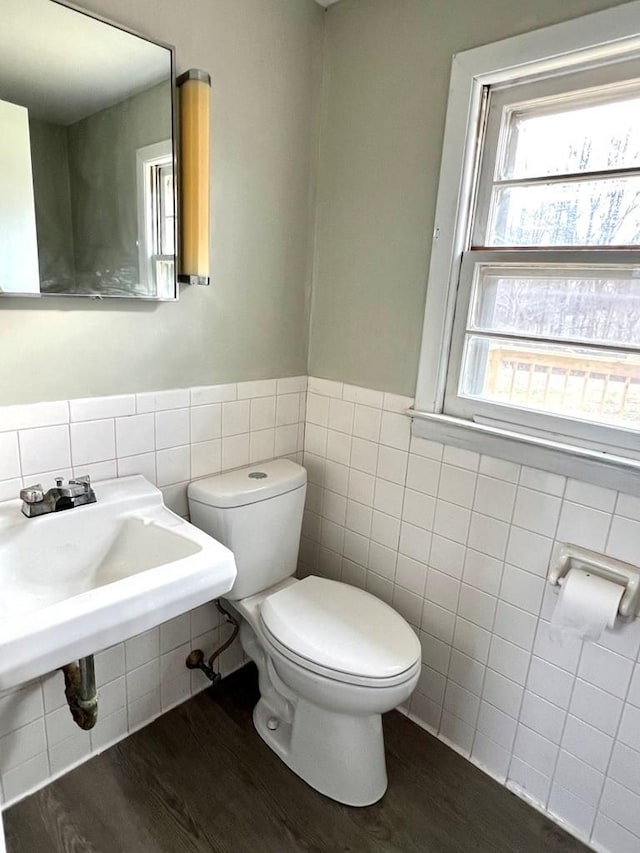 bathroom with hardwood / wood-style flooring, toilet, and tile walls