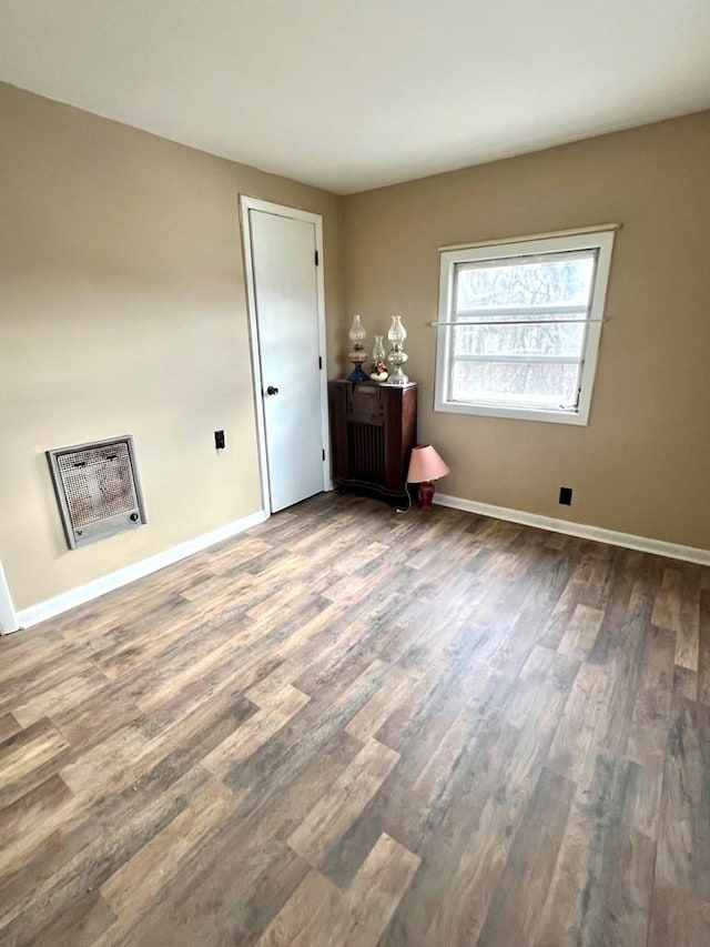 empty room featuring heating unit and hardwood / wood-style flooring