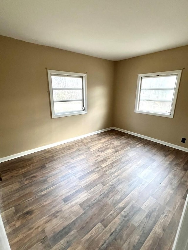 spare room with dark hardwood / wood-style flooring and a healthy amount of sunlight