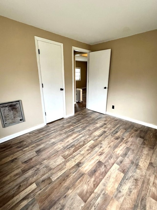 unfurnished bedroom featuring heating unit, radiator heating unit, and wood-type flooring