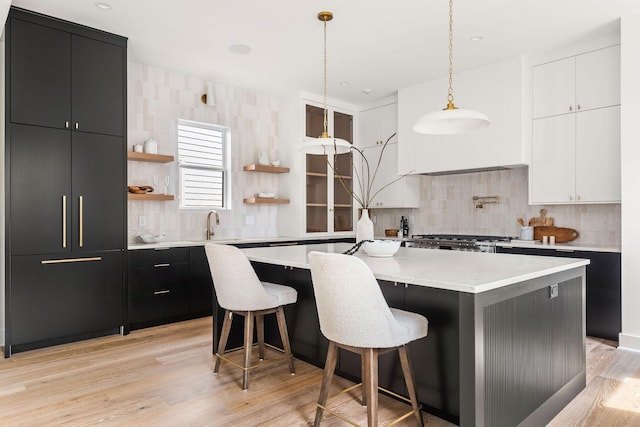 kitchen with white cabinetry, a kitchen island with sink, a breakfast bar area, and pendant lighting