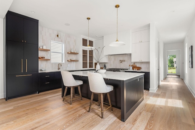 kitchen with a center island with sink, a kitchen breakfast bar, white cabinets, and decorative backsplash