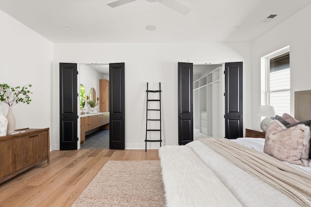 bedroom with ensuite bath, ceiling fan, and light hardwood / wood-style floors