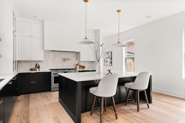 kitchen featuring a kitchen island, a kitchen breakfast bar, decorative light fixtures, range with two ovens, and white cabinets