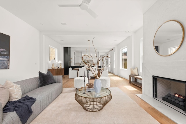 living room featuring a fireplace, light hardwood / wood-style flooring, and ceiling fan