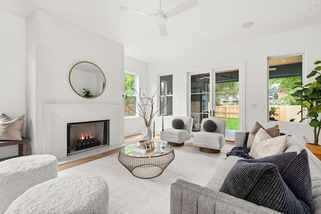 living room featuring a high end fireplace, light hardwood / wood-style flooring, and ceiling fan