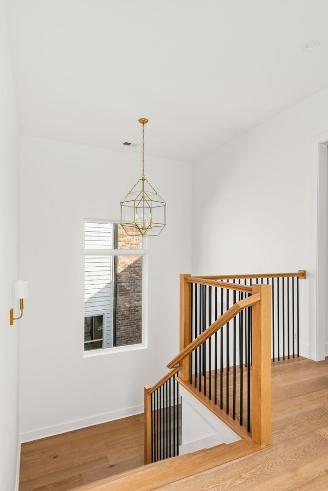 staircase featuring hardwood / wood-style floors and a chandelier