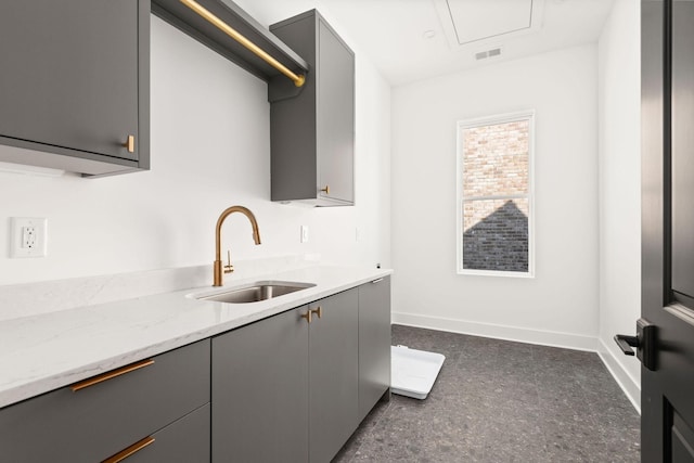 kitchen with gray cabinets, light stone countertops, and sink