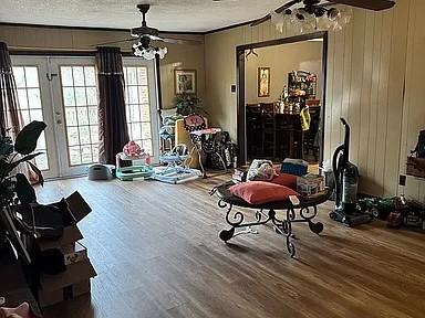 interior space with ceiling fan, wood-type flooring, wooden walls, and a textured ceiling