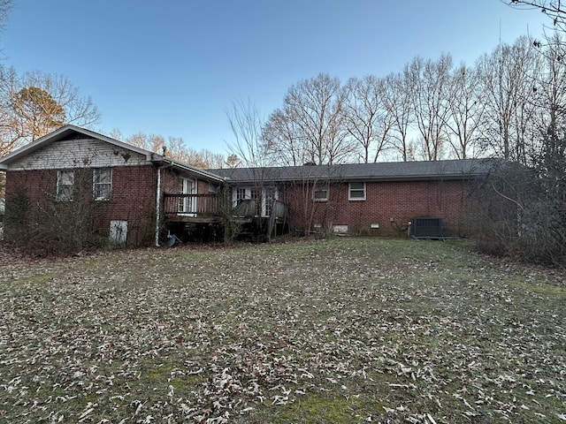 rear view of property featuring central AC unit, a wooden deck, and a yard