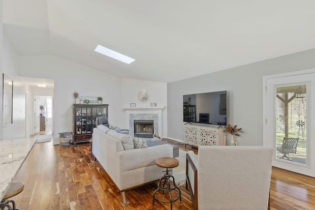 living room with vaulted ceiling with skylight, a fireplace, and hardwood / wood-style flooring